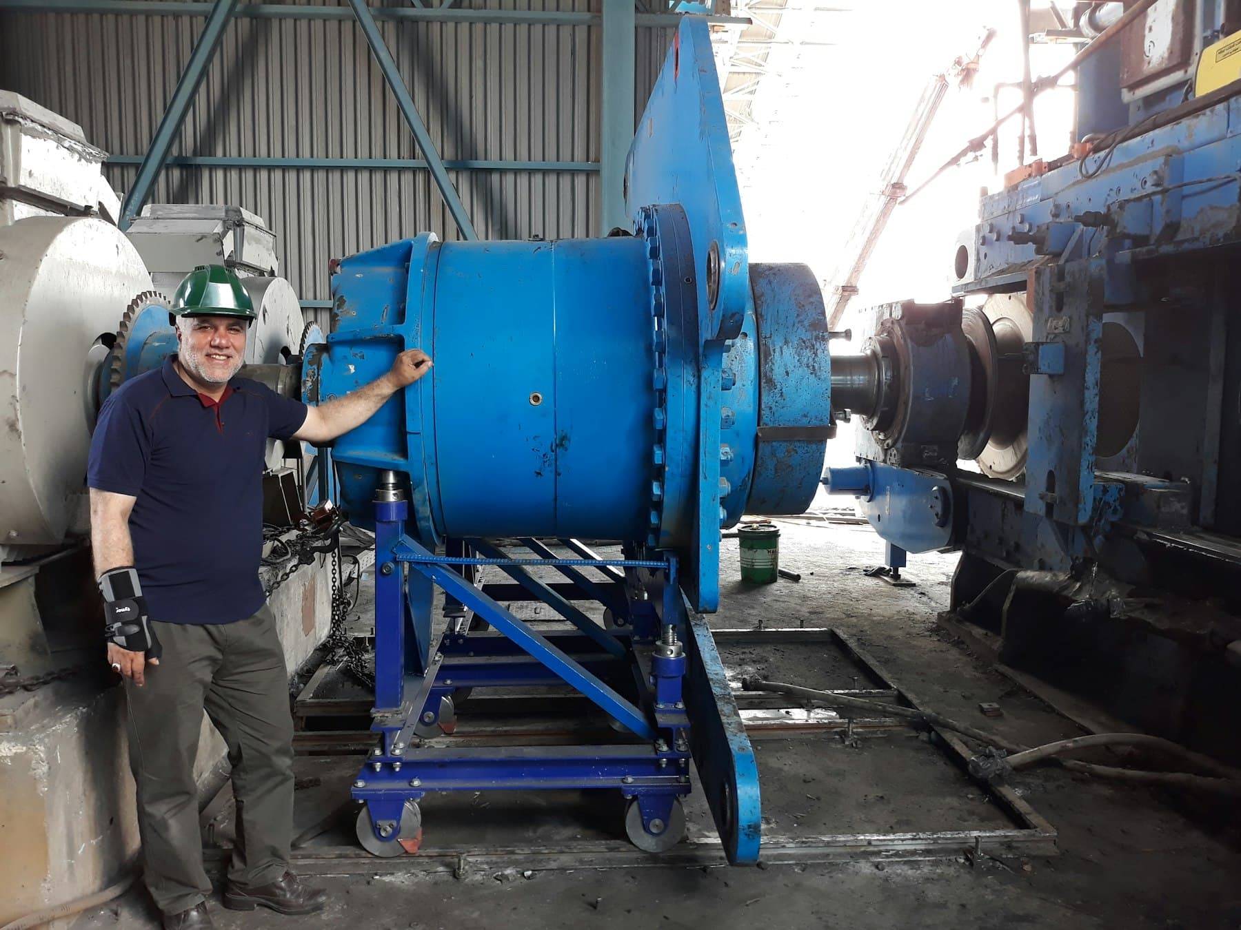 A marine engineer beside a large engine under overhaul in the workshop