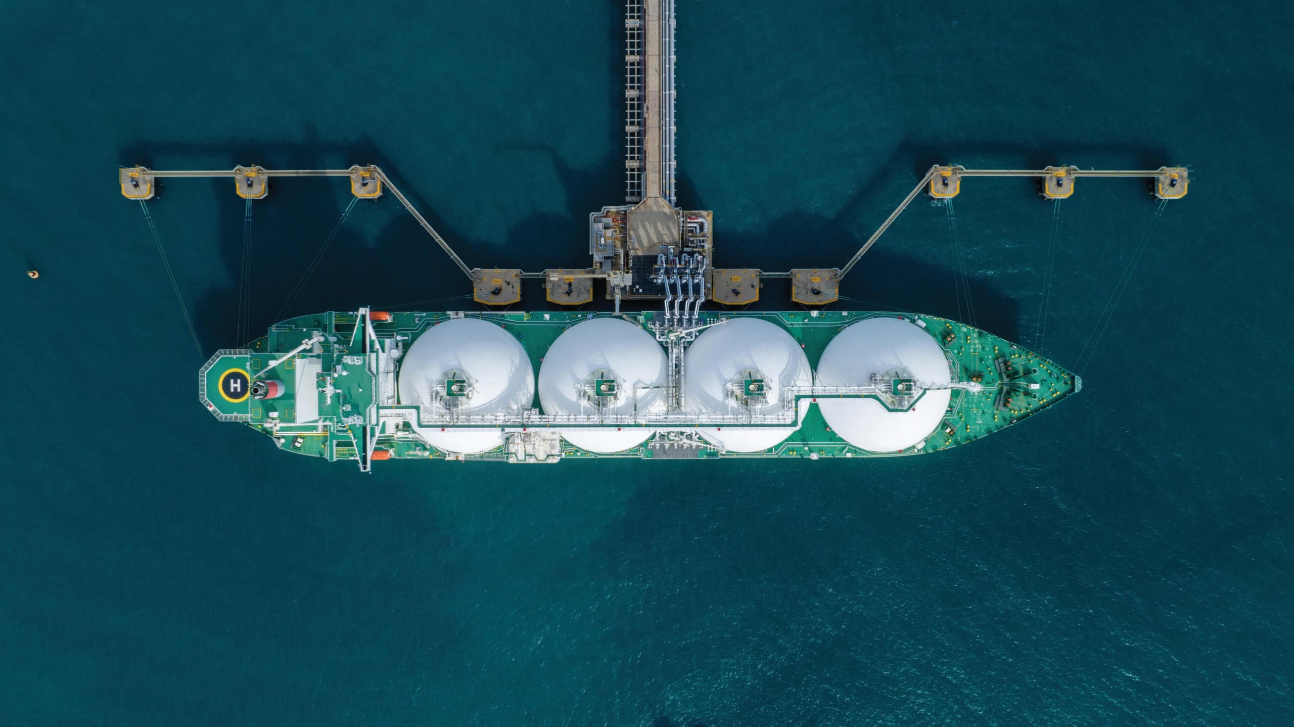 Aerial view of a Moss-type LNG carrier moored at a loading terminal